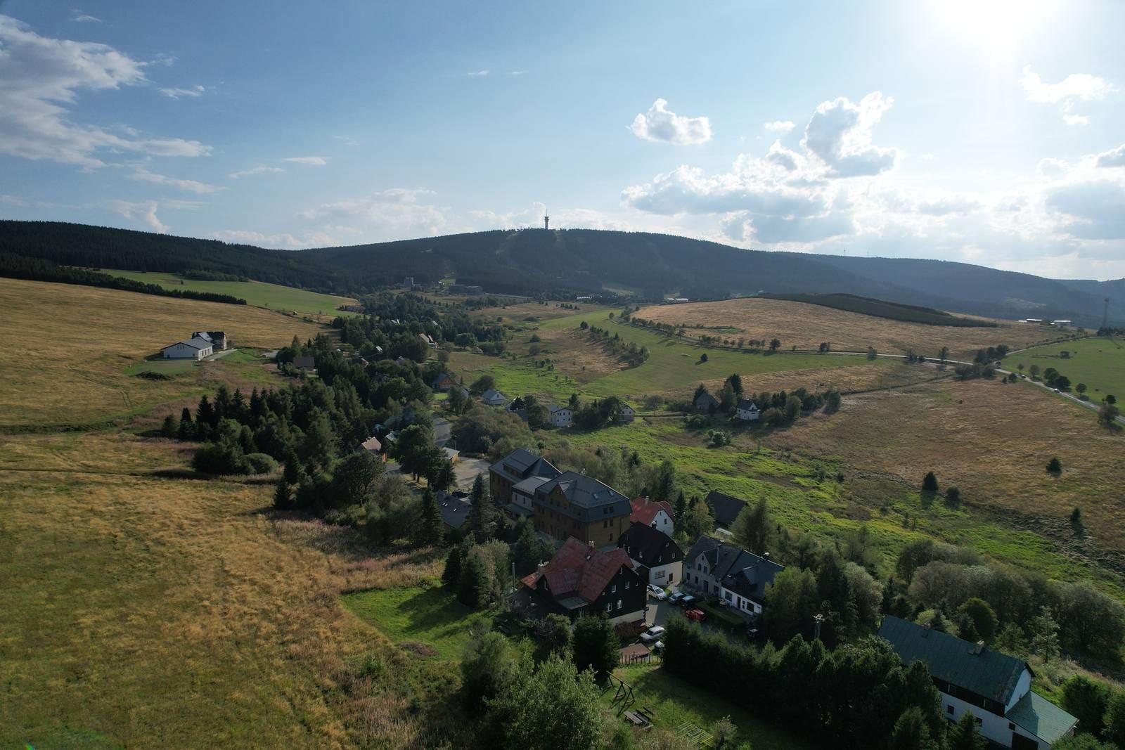 Letecký pohled na Háj u Loučné pod Klínovcem s hotýlkem Arnica v popředí a Klínovcem s rozhlednou v pozadí